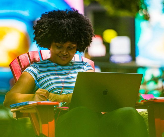 student on their laptop in the sun