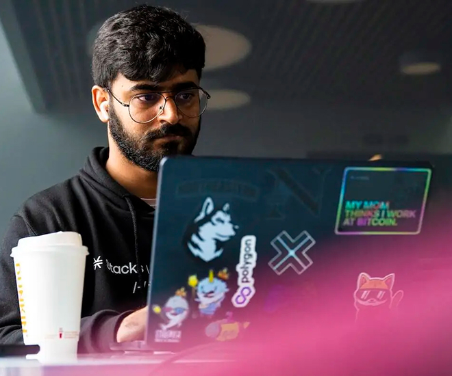 Student sits and works at laptop covered in Northeastern stickers