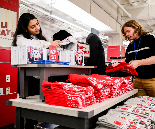 Two people browse shelves of Northeastern gear