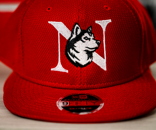 Close up of a red billed hat with the monogram husky logo