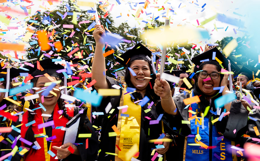 Graduates celebrating together in their caps and gowns with confetti in the air