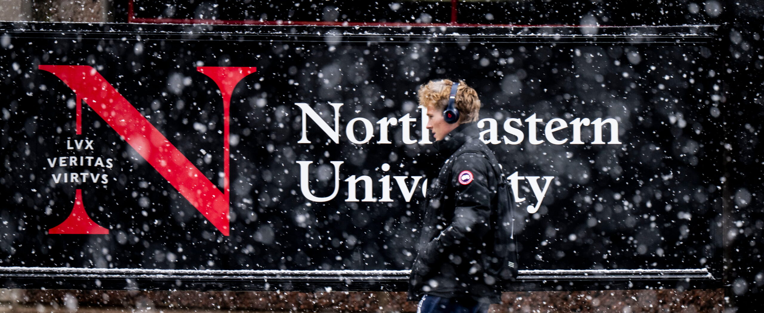 Student walking past a snowy campus banner