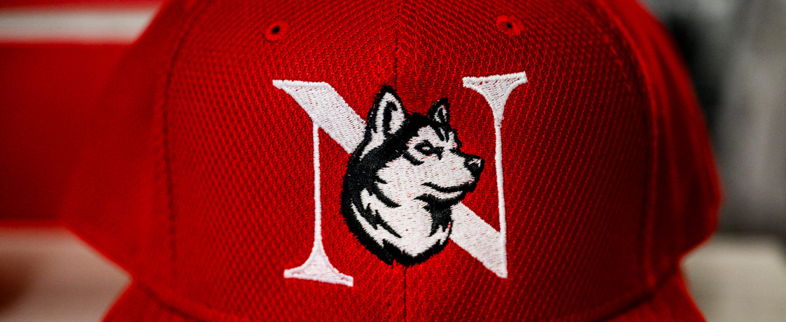 Close up of a red billed hat with the monogram husky logo