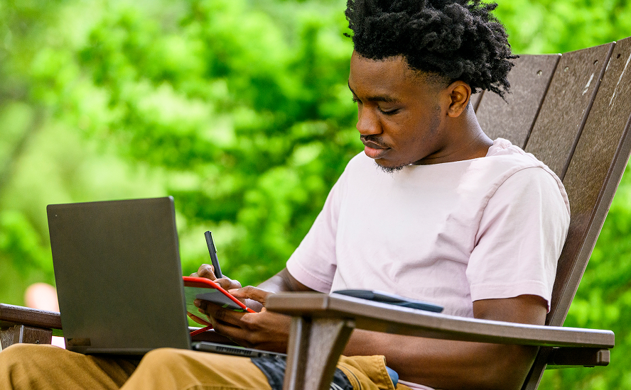 Student sitting outside with their laptop.