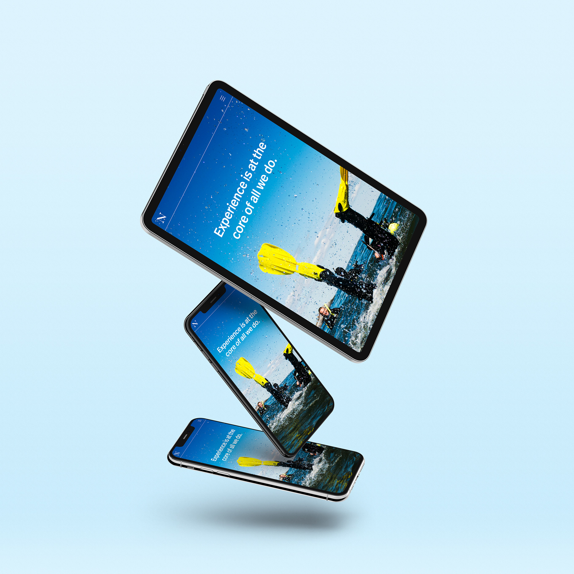 Three stacked devices — a tablet and two smartphones — floating at diagonal angles against a light blue background, each displaying a scuba diving website hero screen with the headline 'Experience is at the core of all we do' overlaid on a photo of a diver emerging from the ocean wearing yellow fins.