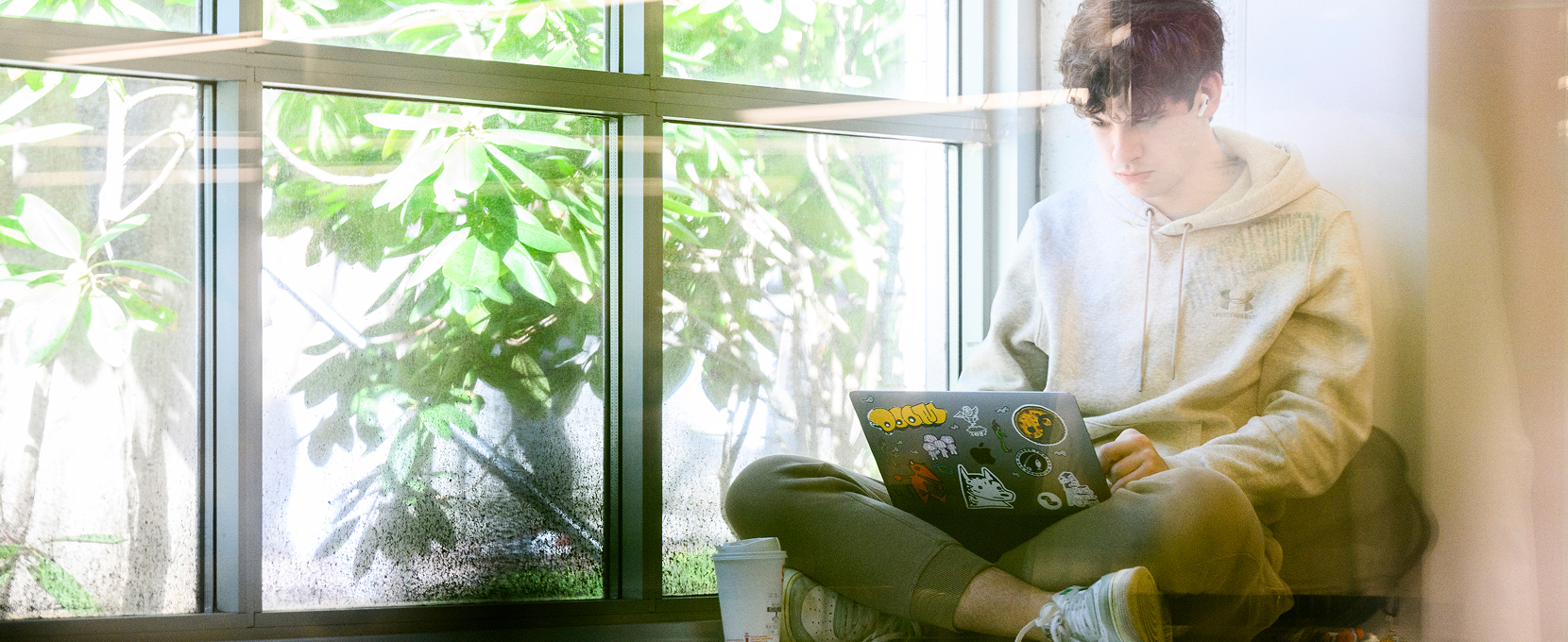 student studying on a windowsill with their laptop